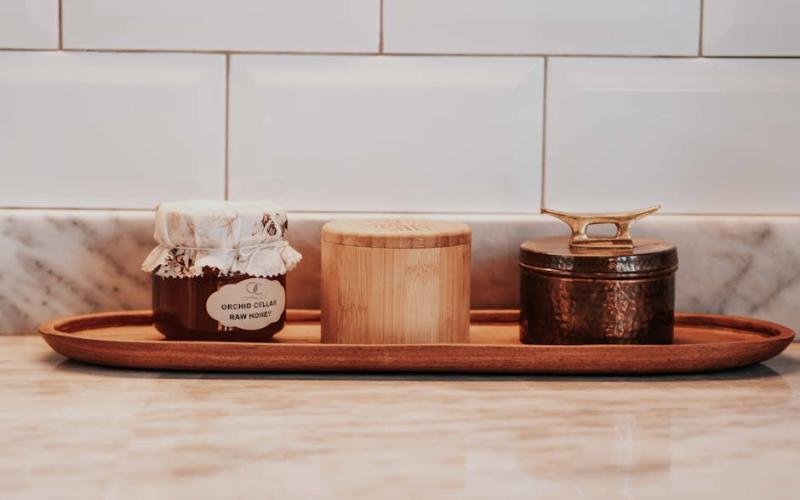 A cozy kitchen setting with a jar of raw honey and decorative containers on a tray.