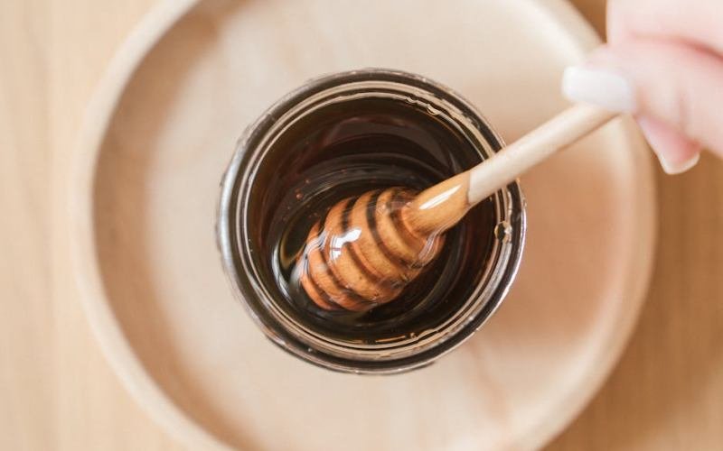 Top view of honey dipper in a jar, perfect for culinary and food themes.