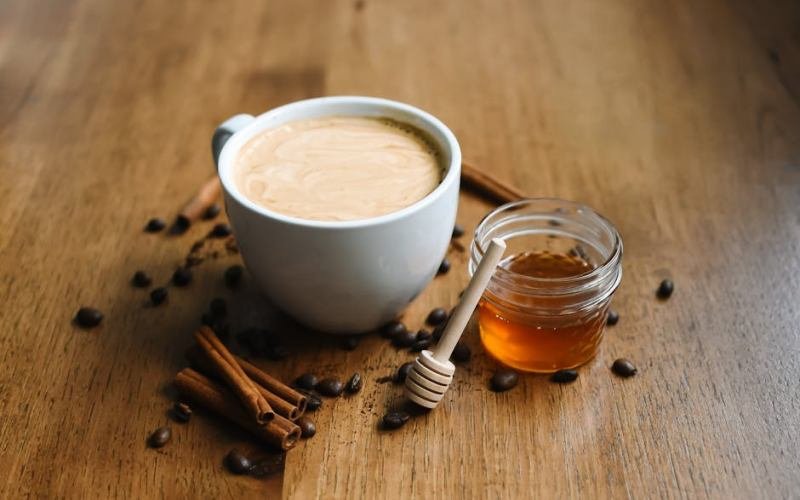 A comforting cup of coffee with cinnamon and honey on a wooden table, perfect for cozy moments.