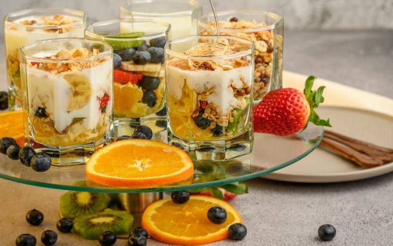 Delicious yogurt parfaits with fresh fruits and granola on a modern platter.