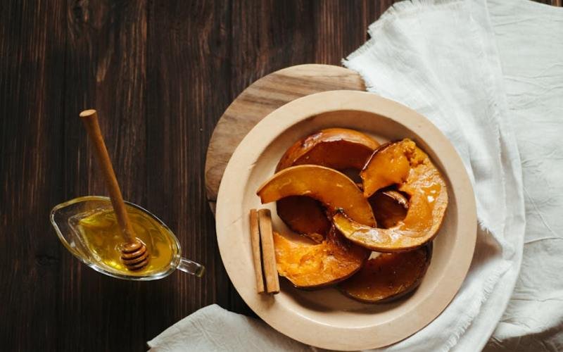 Delicious baked pumpkin slices with honey and cinnamon on a rustic wooden table.