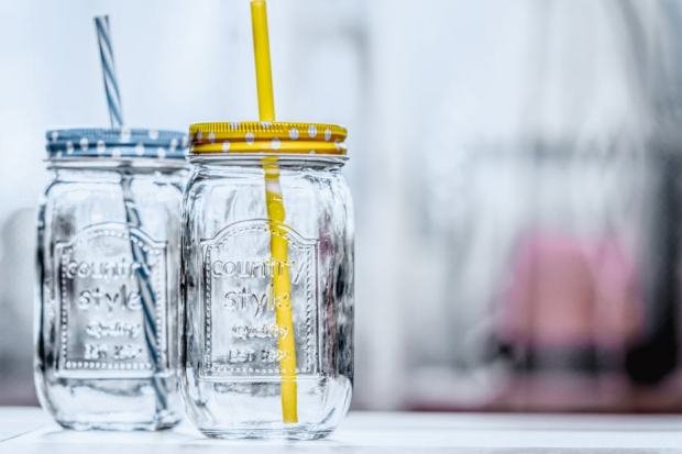 Close-up of two glass jars with polka dot lids and straws, offering a rustic aesthetic.