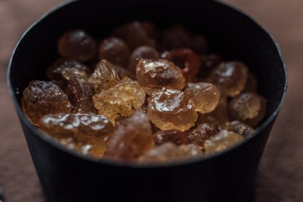 A detailed close-up of brown rock sugar crystals inside a black container, showcasing texture and color contrast.