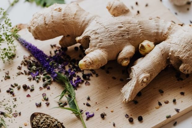 Close-up of fresh ginger and various spices laid out on a chopping board for culinary use.